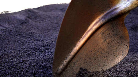Close-up,working men shoveling black gravel for laying asphalt on the road and sidewalk,working outdoors,hard work.の写真素材
