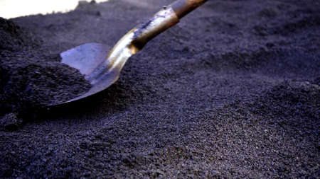 Close-up,working men shoveling black gravel for laying asphalt on the road and sidewalk,working outdoors,hard work.の写真素材