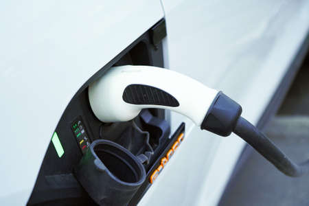 Charging a white electric car close-up.Altrernative eco energy fuel.Power supply connect to electric car for add charge to the battery.Eco-friendly alternative energy conceptの写真素材