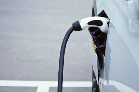 Charging a white electric car close-up.Altrernative eco energy fuel.Power supply connect to electric car for add charge to the battery.Eco-friendly alternative energy conceptの写真素材