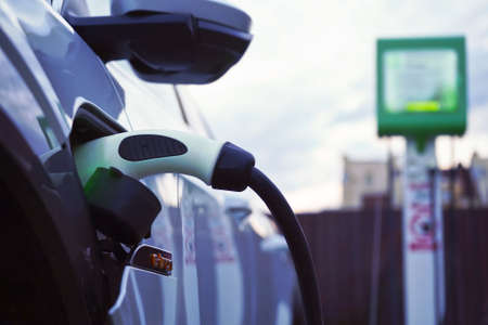 Charging a white electric car close-up.Altrernative eco energy fuel.Power supply connect to electric car for add charge to the battery.Eco-friendly alternative energy conceptの写真素材