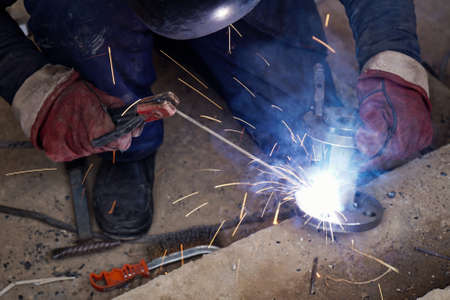 Close-up welder working with electrode at semi-automatic arc welding in manufacture production...