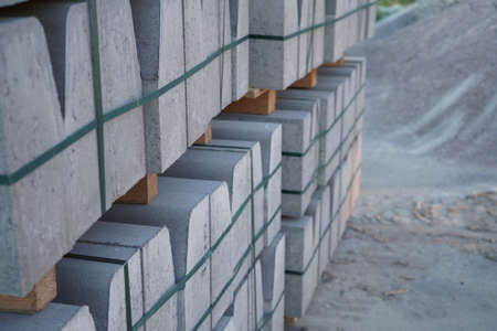 Concrete curbs on wooden pallets stand on the street during street repair. Road works, sidewalk...