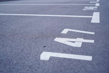 Close-up of white paint markings on parking lot.Empty car parking, Car parking lot with white mark, Parking lane outdoor in public park. Selective focus.の写真素材