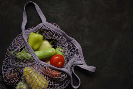 Gray bag string bag with vegetables, zucchini, bell peppers, carrots, beets, onions black background.Harvest from garden fresh bright vegetables.Concept zero waste. Copy space.Top view. Flat lay.の写真素材