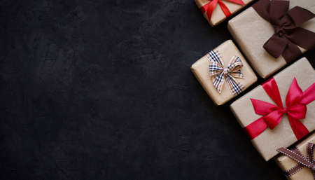 Many gift boxes wrapped in brown paper and tied with different ribbons on a black background, top view, copy space.Christmas and New Year concept.Flatlay, overheard.の写真素材