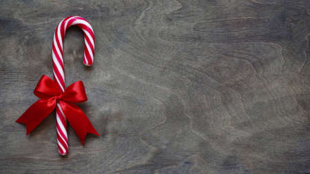 Christmas lollipop with red bow on wooden brown background, copy space, top view, flat lay. Christmas and New Year decor concept.の写真素材