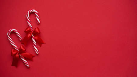 Christmas lollipop with red bow on red background, copy space, top view, flat lay. Christmas and New Year decor concept.の写真素材