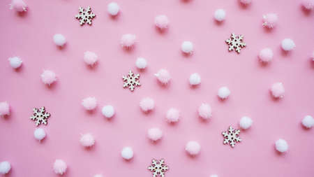 Christmas white snowflakes and pink fluffy pom poms on pink background, pattern, top view, flat lay.Winter festive background concept.の写真素材