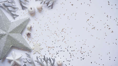Christmas and New Year white and silver decorations among sparkles on white background, top view,...