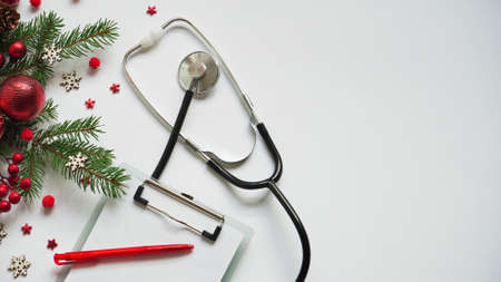 Christmas medical banner fir branches, cones, red balls, snowflakes, stethoscope and tablet on white background top view. Copyspace. Medicine new year flatly.の写真素材