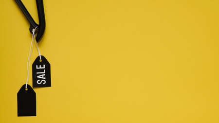 Banner concept for Black Friday celebration, lettering. Black clothes hanger with black blank tags...