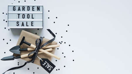 Banner concept for Black Friday celebration, lettering.White board with text GARDEN TOOL SALE, gift...