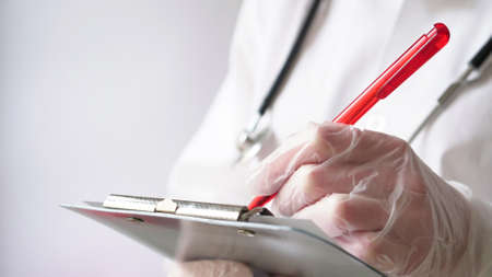 Close-up of a doctor writing a prescription in a medical record on a tablet.の写真素材