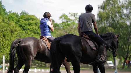 Young man and girl rider brown and black horse in equestrian sport competition.Horse riding on...