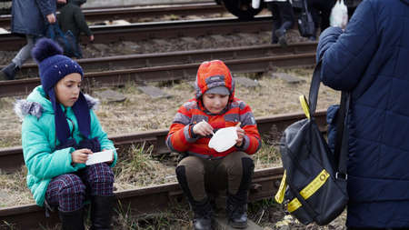 03.03.2022 Ukraine, women fed their little children while sitting on the railway tracks during the evacuation from Ukraine to Poland.Ukrainian refugees. war. Russia attacked Ukraineのeditorial素材