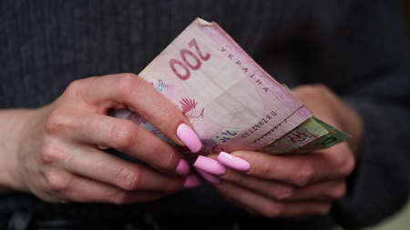 Close-up of female hands holding hryvnia banknotes, Ukrainian currency. The concept of currency...