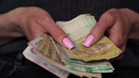Close-up of female hands holding hryvnia banknotes, Ukrainian currency. The concept of currency...