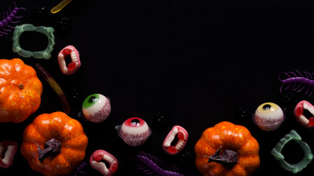Pumpkins,cauldrons,pots,worms,jaws,spiders and candy in the form of eyes on a black background,top view,copy space.Collection of items for a Halloween party.Holiday card.の写真素材