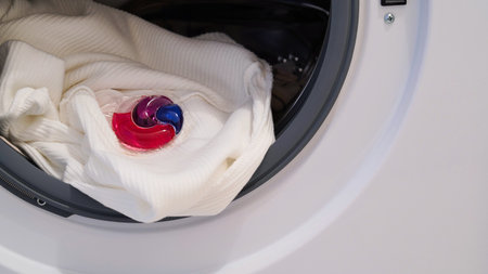 The capsule with the washing gel lies in the drum of the washing machine.Colorful laundry eco gel in capsule. Wash clothers.の写真素材