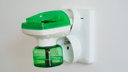 Close-up an electric green fumigator in socket protect against insect bites on white wall background,selective soft focus.Household electric fumigator raptor for protection against mosquitoes at homeの写真素材