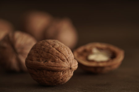 Close-up of walnut kernels and shelled nuts on a wooden table on a dark background.Healthy food, quick snackの写真素材