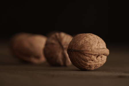 Close-up of walnut kernels and shelled nuts on a wooden table on a dark background.Healthy food,...