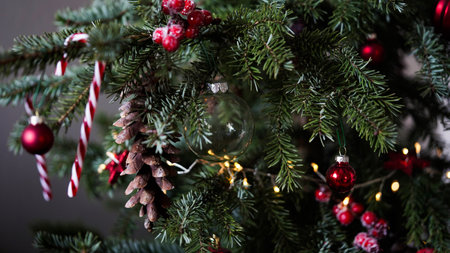 Close-up of a beautiful Christmas tree decorated with red balls, pine cones and candy canes on a gray background. Background concept for Christmas and New Year holidays. The winter vacation.の写真素材