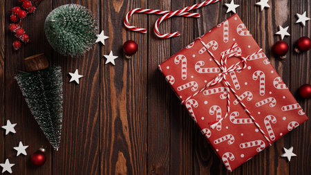 Close-up of Christmas gifts lie on a brown wooden table among holiday decor, fir trees, balls, stars and striped candies, top view, flat lay, copy space. Christmas and New Year banner conceptの写真素材