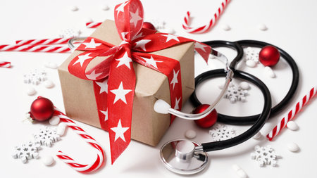 Christmas medical banner.Close-up of stethoscope,gift box,stripped lollipops,red balls,stars and pills on white background,top view,flat lay,copy space.New Year's medicine, congratulations to doctorの写真素材