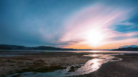 Sunset at Trondheim fjord with halo optical effect over the sun . The picture taken in the Gaulosen nature reserve during low tide at fjord.の写真素材