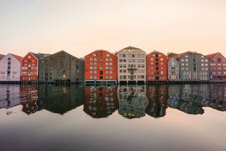 River Nidelva and old timber buildings along the river in the Norwegian city trondheim during sunsetの写真素材