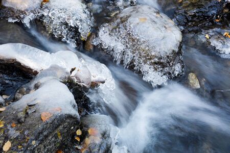 Stream in the mountains, stones covered with frost and ice in October の写真素材