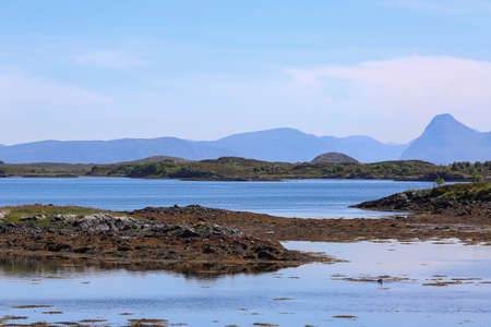 Seaside on the island Smoela and the view of the mountains massive in the Aure municipality, Norway