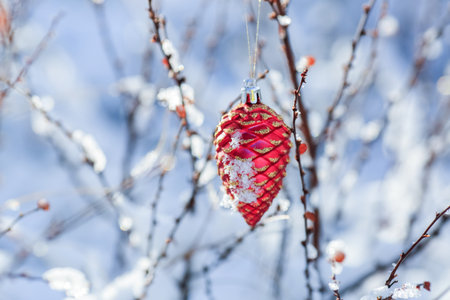 Christmas toy on the  branch in the snowy sunny winter forest