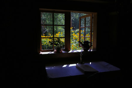 Open window in the old wooden house with summer garden. Sunlight, the table covered with white...