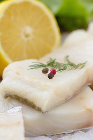 Raw fish with vegetables, lemon and seasonings on the wooden tableの写真素材