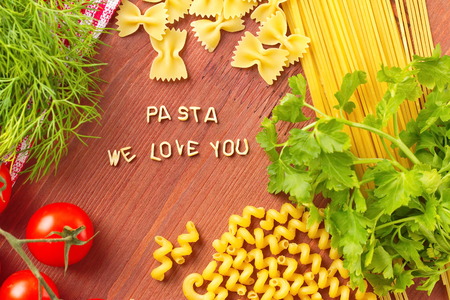 Cooking with love. Different kinds of pasta and fresh vegetables on wooden background.の写真素材