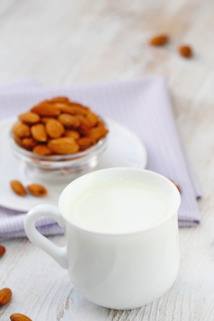 Almond milk in mug and almonds on tableの写真素材