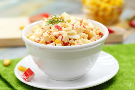Traditional Russian salad with crab sticks and sweet corn in white bowl. National cuisine.の写真素材