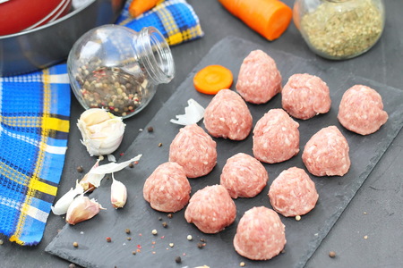Raw meatballs on a chopping board with ingredients ready for cookの写真素材