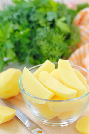 Raw peeled potatoes in bowl ready for cookingの写真素材