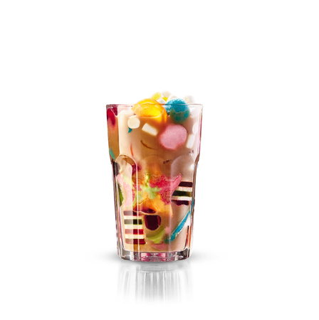 Monster shake, freak caramel shake isolated. Colourful, festive milk shake cocktail with sweets, jelly. Colored caramel milkshake array of different childs sweets and treats in glass on white background. Sweet candy milkshake. Crazy freakshake food trend.の写真素材