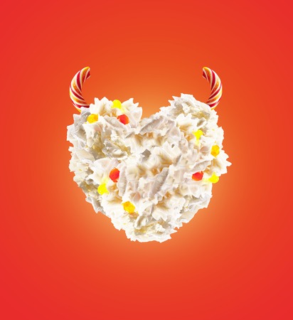 Devil heart Milk shake with sweets and whipped cream, front view. Sweet concept with whipped cream and devil horns, devil sweats. Front view of whipped cream, full of berry and jelly sweets. Colored whipped devil cream concept.の写真素材