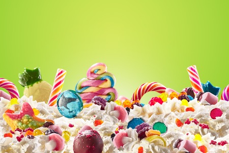 Milk shake with sweets and whipped cream, front view. Crazy freakshake food trend. Top view of whipped cream, full of berry and jelly sweets, chocolate candy. Colored whipped cream concept. Monster shake, freak shake conceptの写真素材
