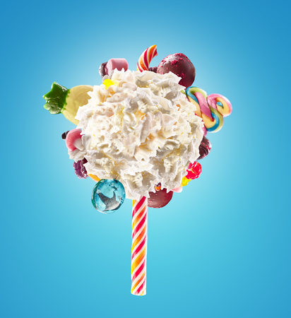 Whipped chantilly cream lolipop concept. Round whipped milk shake cream like lollipop with candy, sweets and candy on border, isolated on bright background. Cream swirl lolly with childs colorful treats, sweet lolipops concept.の写真素材