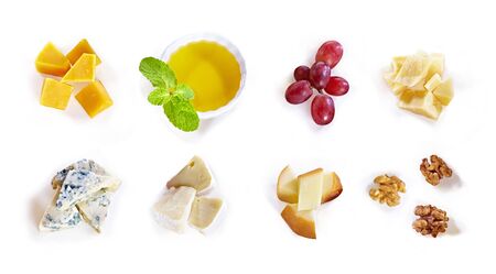 Different type of cheese with honey, grape, nuts on white background. Top view. Blue cheese, cheddar, parmesan, maasdam and brie cheese slicesの写真素材