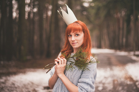 Hipster. Photo redheaded girl with a paper crown on his head. Young woman in forest.の写真素材