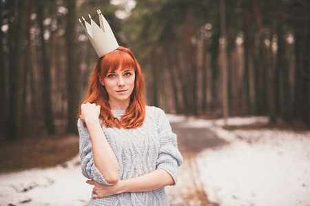 Hipster. Photo redheaded girl with a paper crown on his head. Young woman in forest.の写真素材