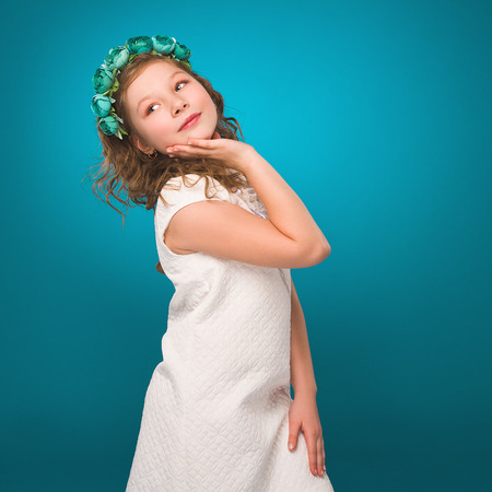 Girl with flower decorations. White dress. Turquoise background.の写真素材